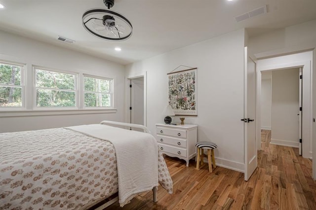 bedroom with baseboards, light wood-type flooring, visible vents, and recessed lighting