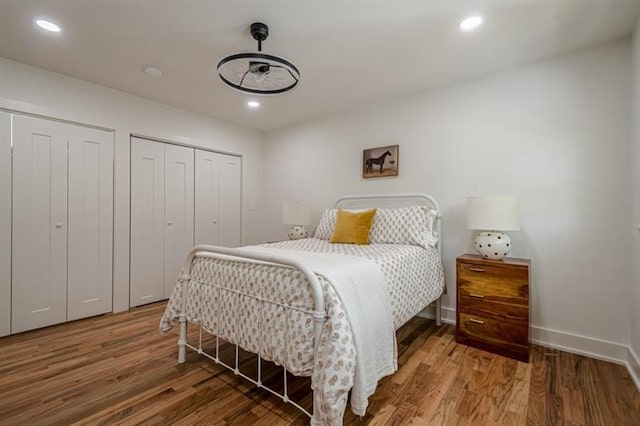 bedroom with wood finished floors, multiple closets, and recessed lighting