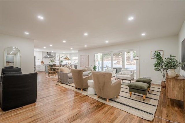 living area featuring light wood-style floors, arched walkways, and recessed lighting