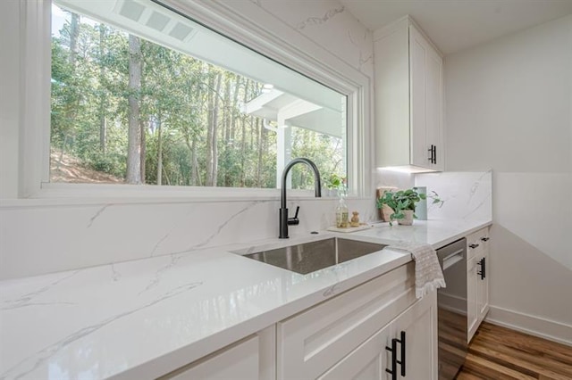kitchen featuring white cabinetry, light stone counters, a sink, and wood finished floors