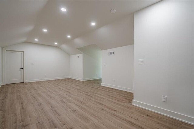 additional living space featuring visible vents, baseboards, light wood-style floors, lofted ceiling, and recessed lighting
