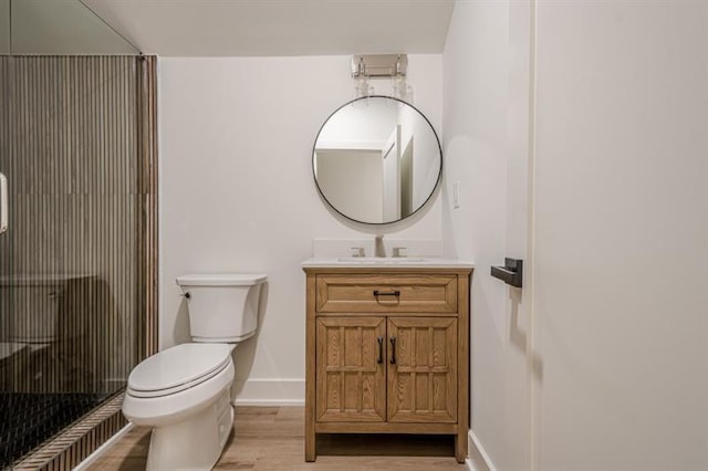 bathroom with toilet, wood finished floors, a stall shower, baseboards, and vanity