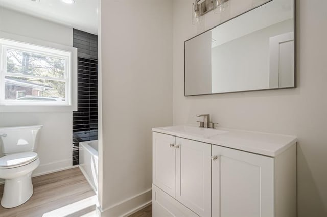 bathroom with toilet, baseboards, wood finished floors, and vanity