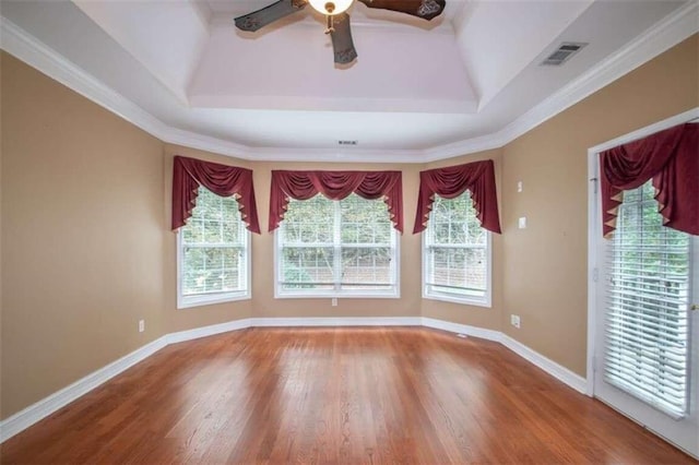 unfurnished dining area with ceiling fan, wood-type flooring, crown molding, and a tray ceiling