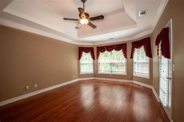 empty room with dark hardwood / wood-style floors, a raised ceiling, ceiling fan, and crown molding