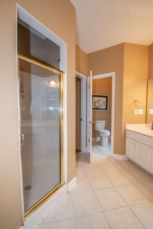 bathroom featuring tile patterned floors, vanity, toilet, and an enclosed shower