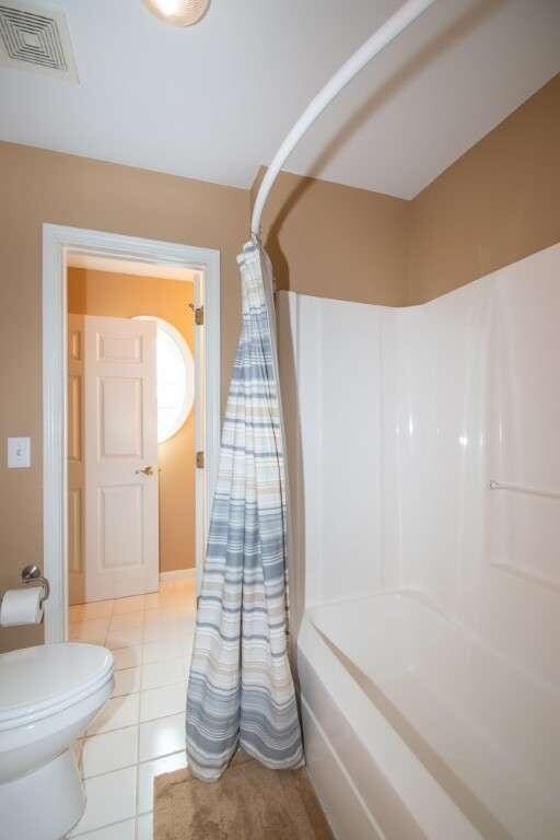 bathroom with tile patterned flooring, shower / bath combo, and toilet