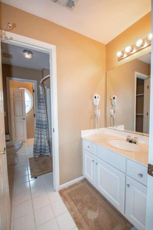 bathroom with tile patterned floors, vanity, curtained shower, and toilet