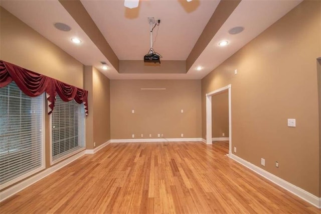 spare room featuring a raised ceiling and light hardwood / wood-style flooring