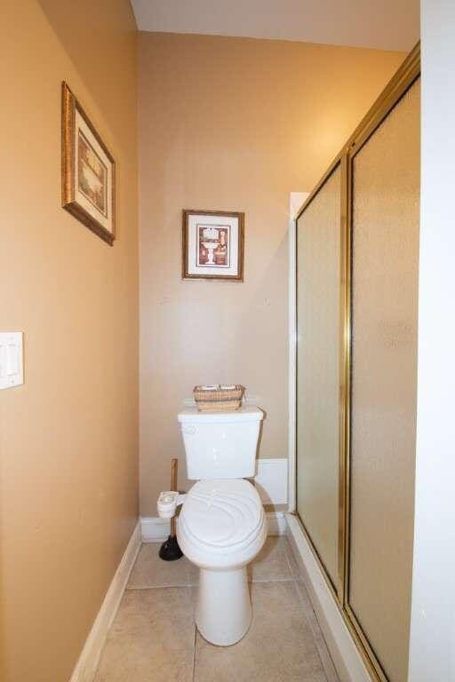 bathroom featuring toilet, tile patterned floors, and a shower with shower door