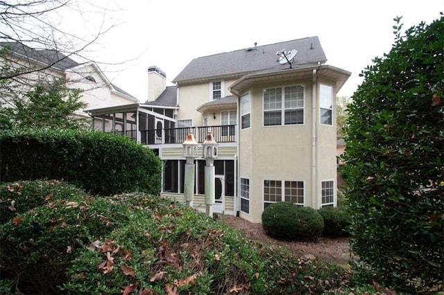 rear view of property featuring a balcony and a sunroom