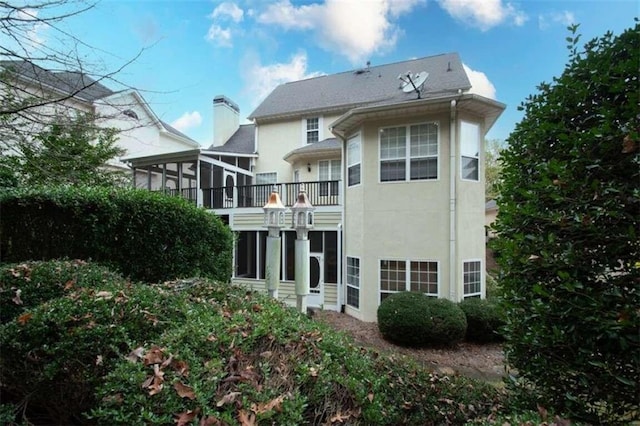 back of property with a sunroom and a balcony