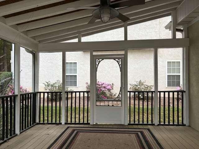 unfurnished sunroom featuring vaulted ceiling with beams, ceiling fan, and plenty of natural light