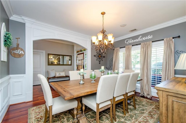 dining space featuring visible vents, crown molding, arched walkways, wood finished floors, and a notable chandelier