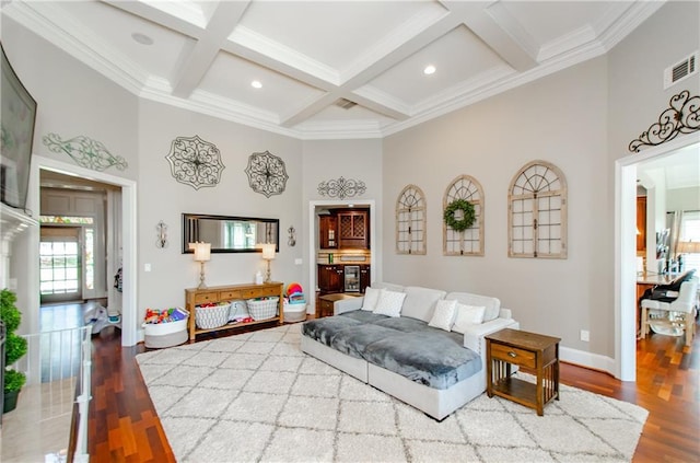 living area featuring crown molding, baseboards, visible vents, and a high ceiling