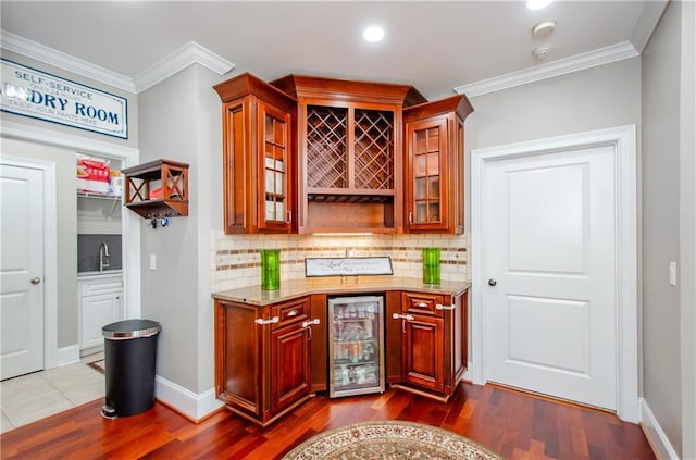 bar featuring decorative backsplash, a bar, beverage cooler, and dark wood-type flooring