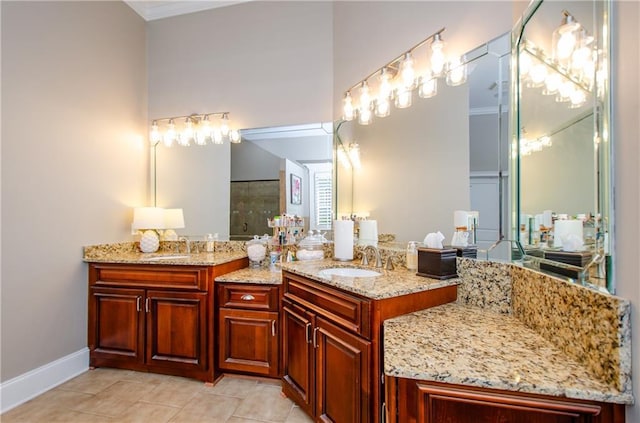 full bathroom with double vanity, baseboards, a sink, and tile patterned flooring