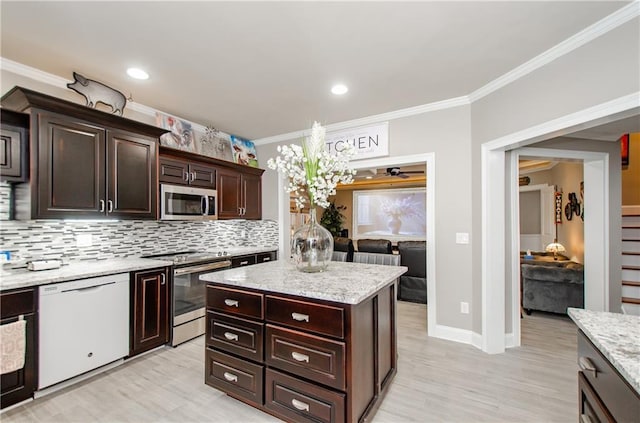 kitchen featuring crown molding, backsplash, stainless steel appliances, and light wood-type flooring