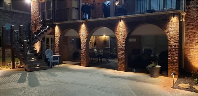 view of patio with stairway and a balcony
