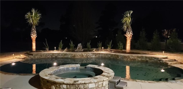 pool at night with an in ground hot tub and an outdoor pool