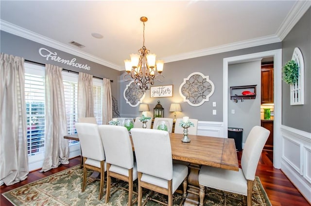 dining space with an inviting chandelier, ornamental molding, a wainscoted wall, and visible vents