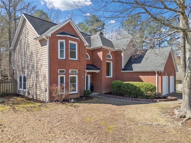 traditional-style home featuring a garage, brick siding, and roof with shingles