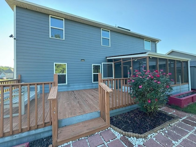 rear view of house featuring a sunroom and a wooden deck