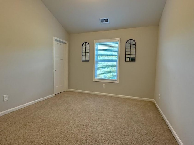 carpeted spare room with vaulted ceiling