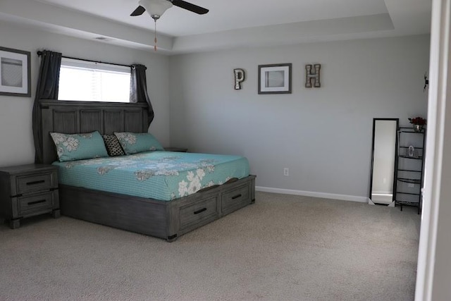 bedroom with light carpet, a raised ceiling, and ceiling fan