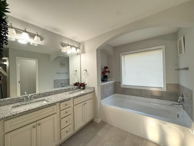 bathroom with tile patterned floors, a bathing tub, and vanity