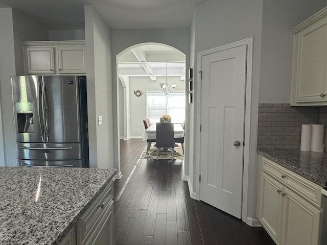 kitchen with beamed ceiling, light stone countertops, stainless steel fridge with ice dispenser, and coffered ceiling