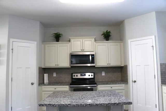 kitchen with light stone countertops, stainless steel appliances, and tasteful backsplash