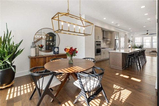 dining space featuring dark hardwood / wood-style flooring, ceiling fan with notable chandelier, and sink