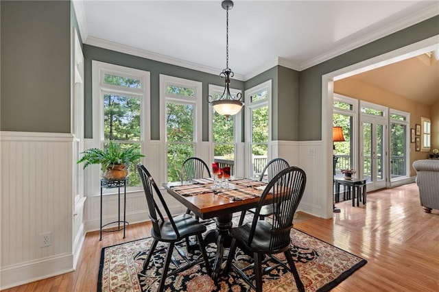 dining area featuring french doors, light wood-type flooring, ornamental molding, and a healthy amount of sunlight