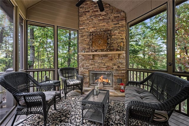 sunroom with ceiling fan, a stone fireplace, vaulted ceiling, and wooden ceiling