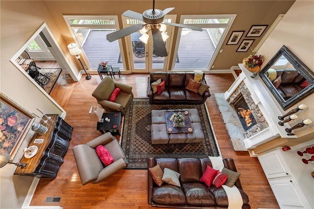 living room featuring ceiling fan, a stone fireplace, and hardwood / wood-style floors