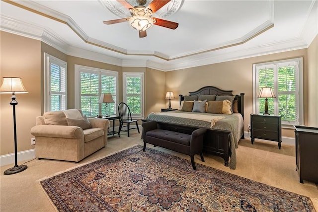 carpeted bedroom featuring multiple windows, a raised ceiling, ornamental molding, and ceiling fan