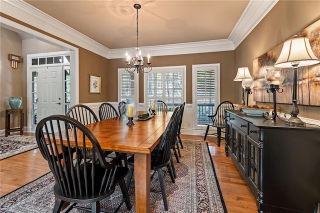 dining area featuring crown molding, light hardwood / wood-style flooring, and a chandelier