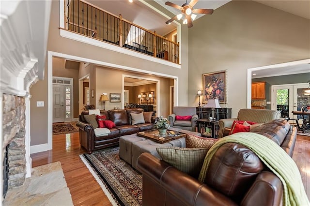 living room featuring high vaulted ceiling, light wood-type flooring, a high end fireplace, and ceiling fan