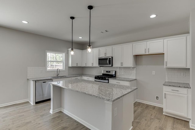 kitchen with a center island, stainless steel appliances, white cabinetry, and sink