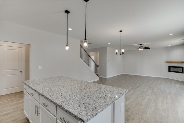 kitchen featuring white cabinetry, ceiling fan, light hardwood / wood-style flooring, pendant lighting, and a kitchen island