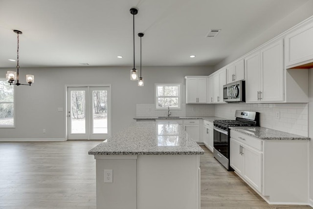 kitchen featuring light stone countertops, sink, tasteful backsplash, white cabinets, and appliances with stainless steel finishes