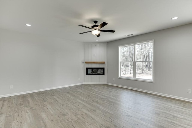 unfurnished living room featuring a fireplace, light hardwood / wood-style floors, and ceiling fan