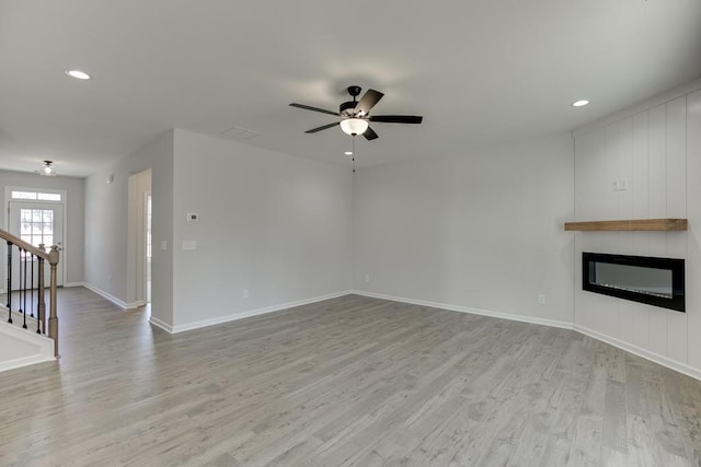 unfurnished living room featuring a fireplace, light hardwood / wood-style floors, and ceiling fan