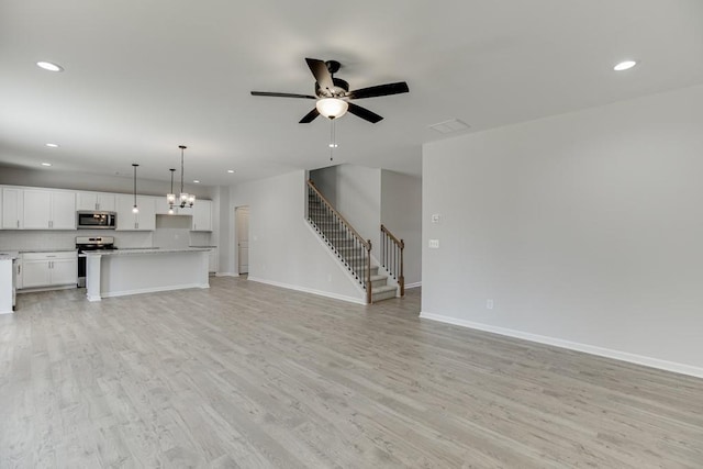 unfurnished living room with ceiling fan with notable chandelier and light wood-type flooring