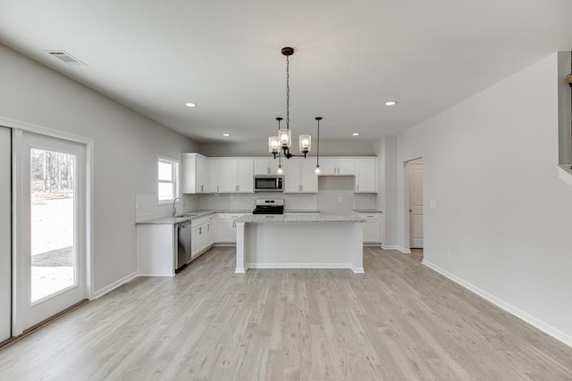 kitchen featuring a kitchen island, white cabinets, decorative light fixtures, and appliances with stainless steel finishes