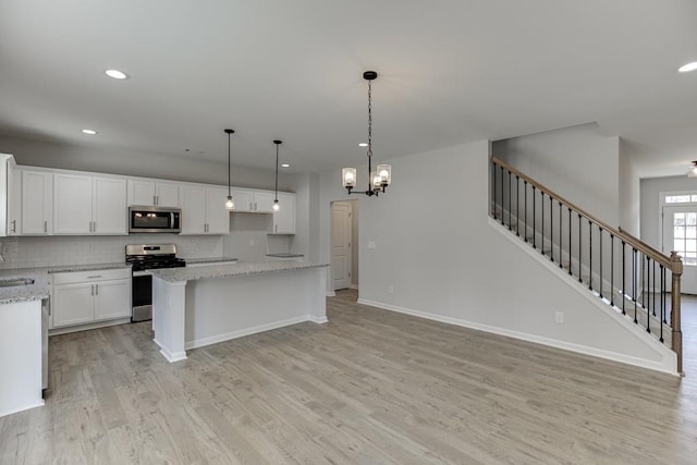 kitchen featuring white cabinets, stainless steel appliances, a kitchen island, and tasteful backsplash