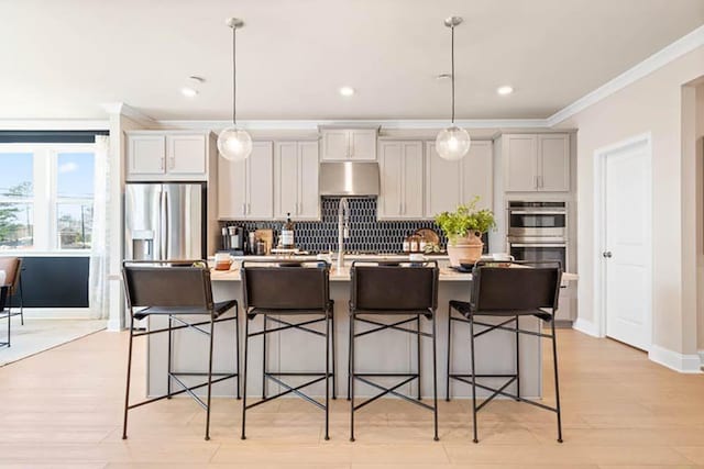 102 Sheryl Way, Loganville, GA 30052 - kitchen featuring appliances with stainless steel finishes, a center island with sink, backsplash, light countertops, and a breakfast bar area