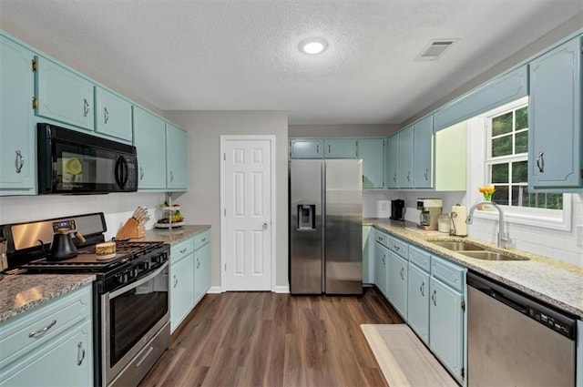 1050 Birdseye Vw, Locust Grove, GA 30248 - kitchen with appliances with stainless steel finishes, a textured ceiling, blue cabinets, dark wood finished floors, and light stone countertops