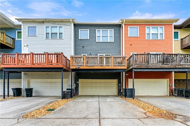 back of house with an attached garage, a balcony, central air condition unit, and driveway